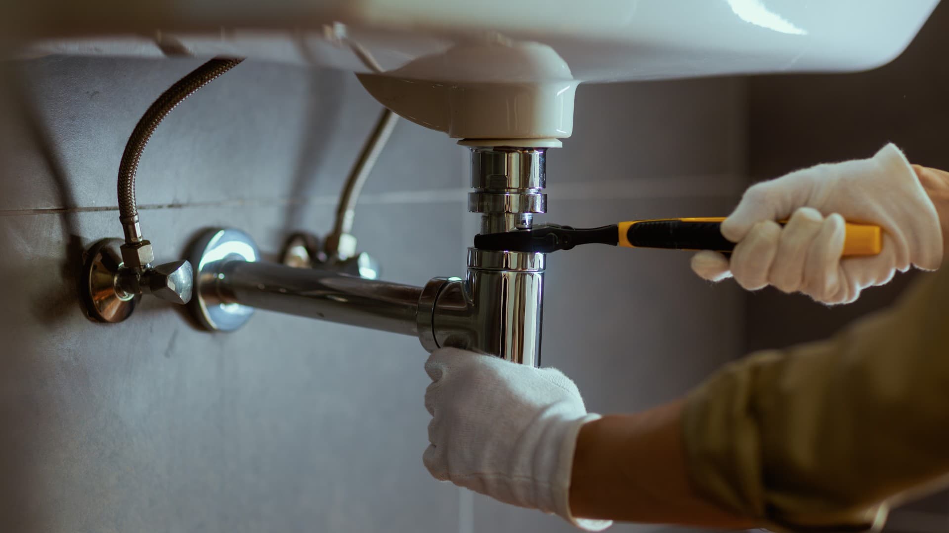 Plumber repairing a pipe fitting under a sink